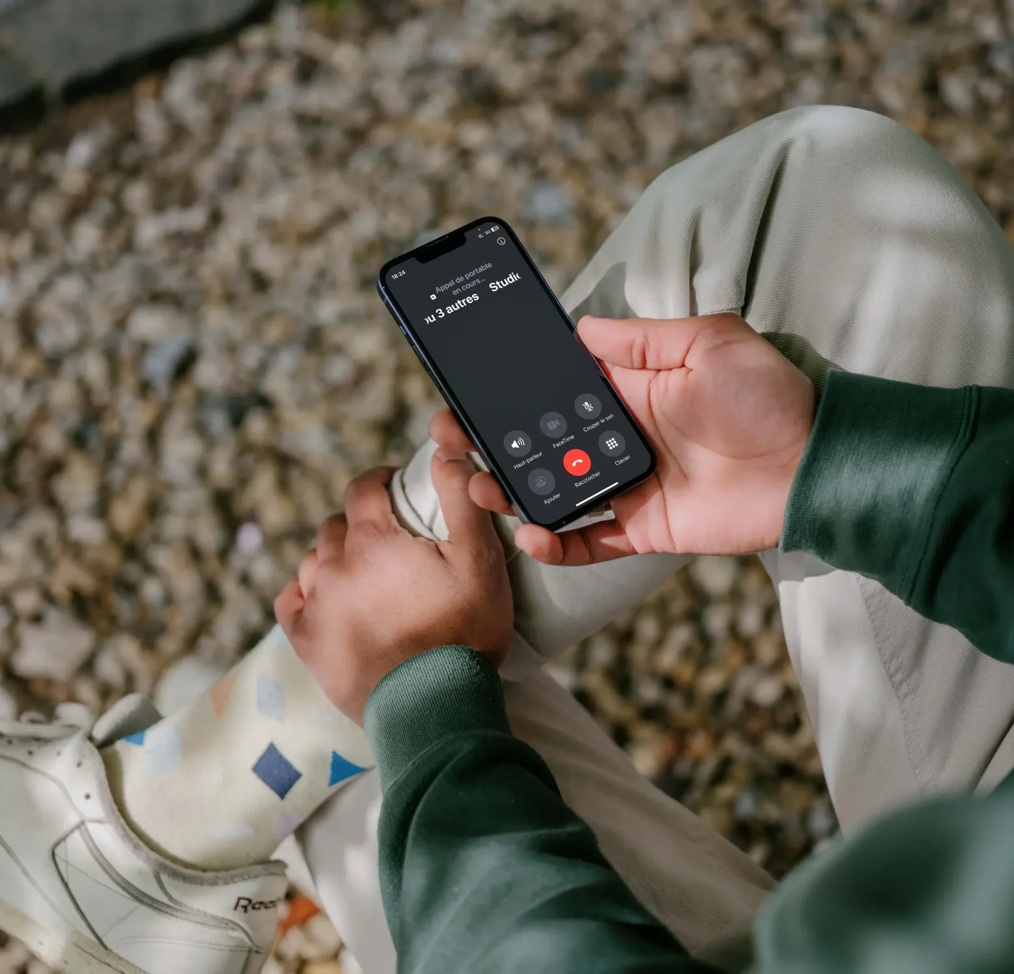 Personne assise à l'extérieur passant un appel sur son téléphone mobile